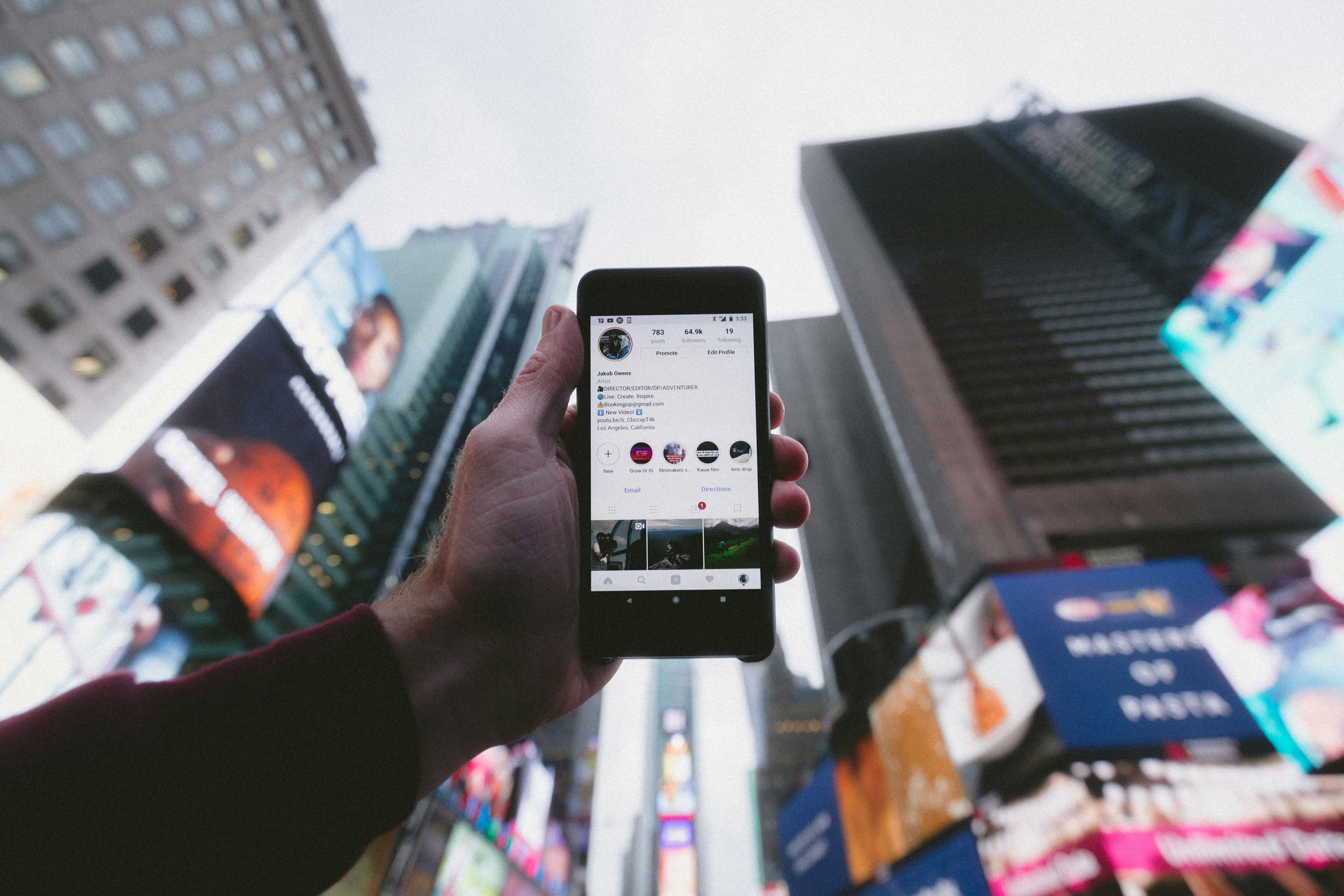 Person holding cellphone with skyscrapers in the background